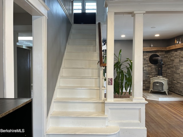 stairway featuring wood finished floors and a wood stove