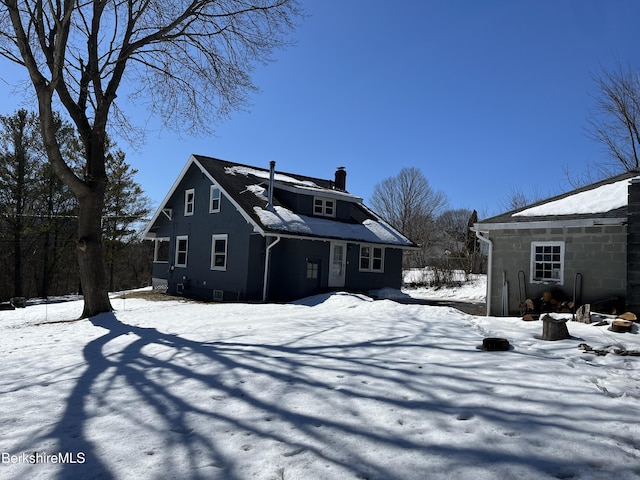 snow covered rear of property with a chimney