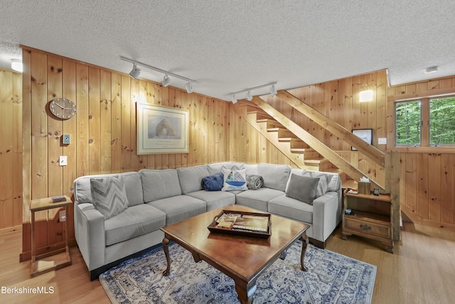 112 Silver St, Lanesborough, MA 01237 - living room with rail lighting, a textured ceiling, stairway, light wood-style floors, and wooden walls