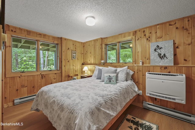 112 Silver St, Lanesborough, MA 01237 - bedroom with baseboard heating, wood finished floors, wood walls, heating unit, and a textured ceiling