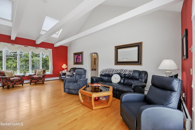 living area with arched walkways, beam ceiling, a skylight, and light wood-style flooring