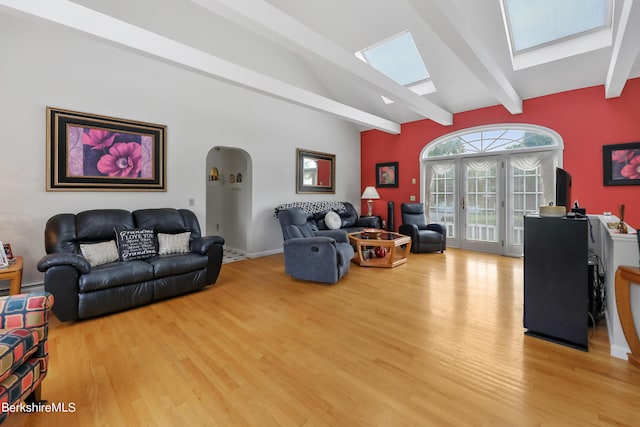 living area featuring vaulted ceiling with skylight, french doors, arched walkways, and wood finished floors