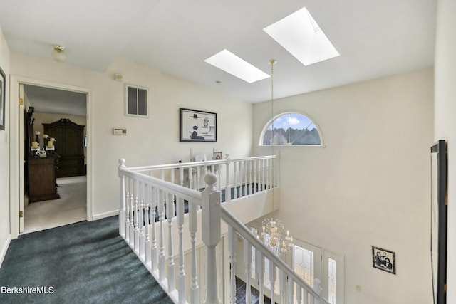 hallway with carpet floors, a notable chandelier, visible vents, an upstairs landing, and baseboards