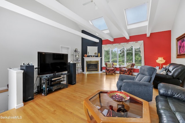 living room with lofted ceiling with skylight, baseboards, light wood-style floors, and a fireplace with flush hearth