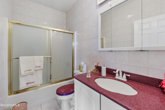 bathroom featuring tasteful backsplash, bath / shower combo with glass door, toilet, vanity, and tile walls