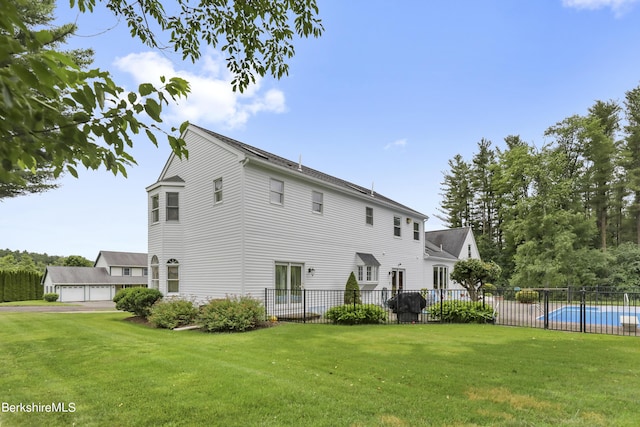 back of house featuring a fenced in pool, fence, and a lawn