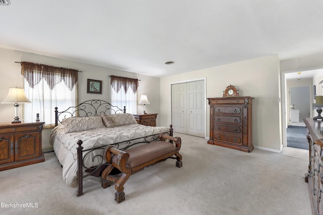 bedroom with baseboards, a closet, and light colored carpet