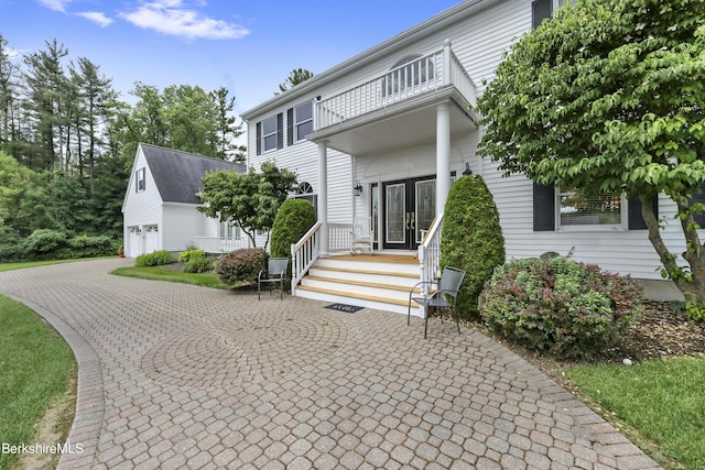 view of front of home with french doors, decorative driveway, an attached garage, and a balcony