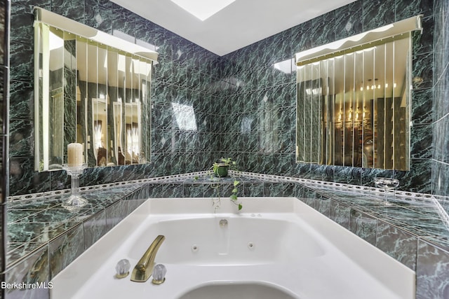 bathroom with a whirlpool tub and tile walls