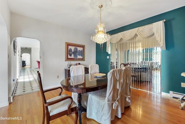 dining room featuring arched walkways, baseboards, an inviting chandelier, and wood finished floors