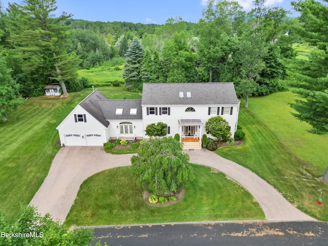 view of front of house featuring roof with shingles, a front lawn, and decorative driveway