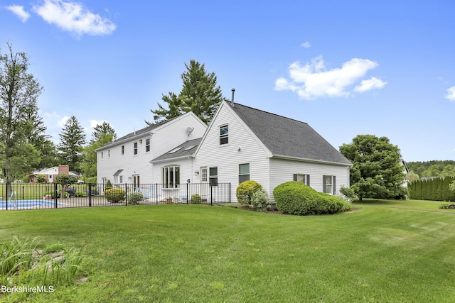 view of front of house with roof with shingles, a front yard, fence, and a fenced in pool