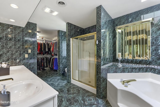 bathroom featuring a garden tub, tile walls, visible vents, a stall shower, and a sink