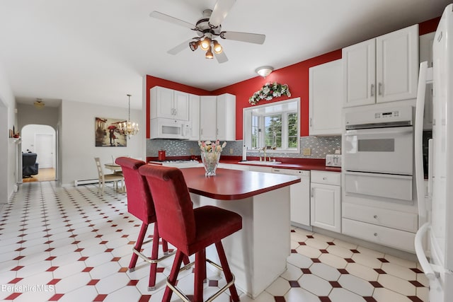 kitchen with arched walkways, a warming drawer, light floors, a sink, and white appliances