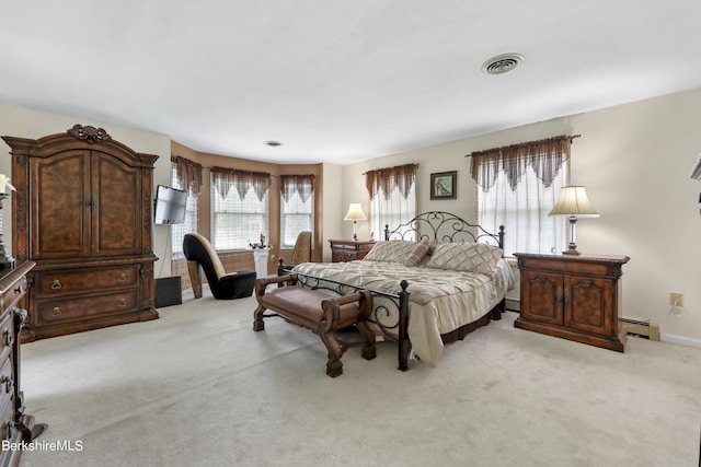 bedroom with a baseboard heating unit, visible vents, and light colored carpet