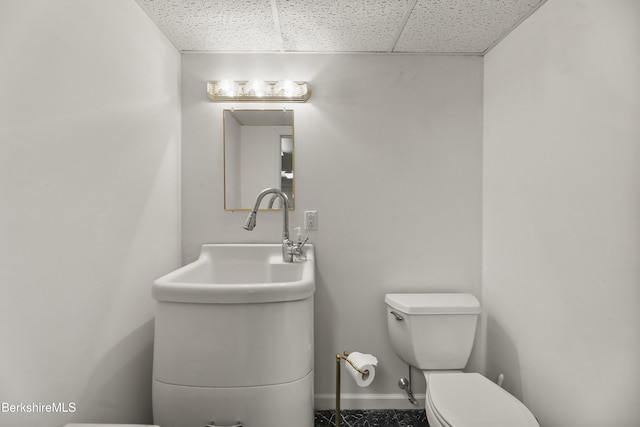 bathroom featuring a paneled ceiling, toilet, and baseboards