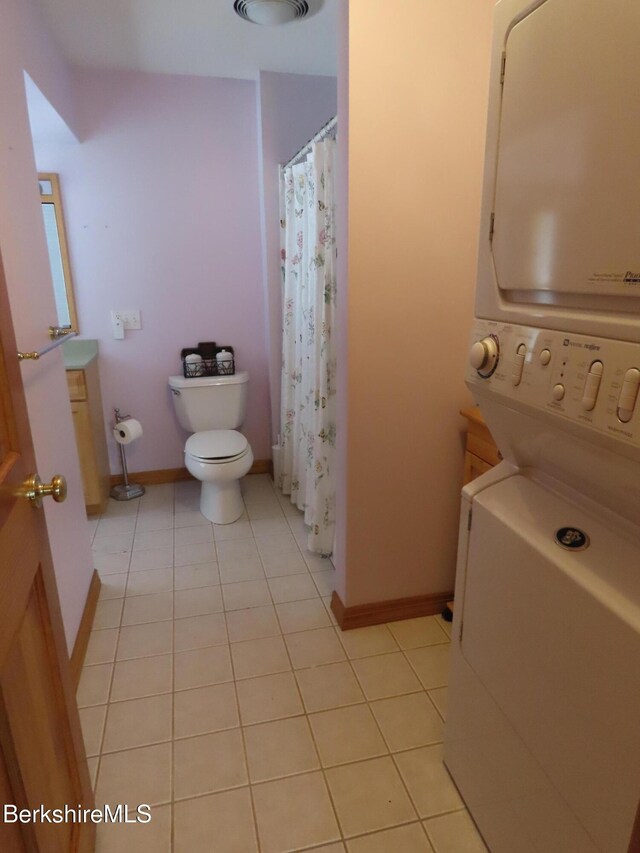 16-18 Hoosac St, Adams, MA 01220 - full bath with estacked washer and dryer, toilet, tile patterned flooring, baseboards, and curtained shower