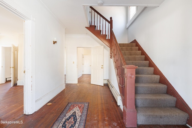 stairs featuring hardwood / wood-style flooring, a baseboard radiator, and ornamental molding