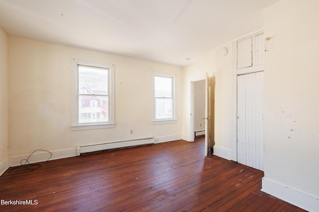 unfurnished room with dark hardwood / wood-style flooring and baseboard heating