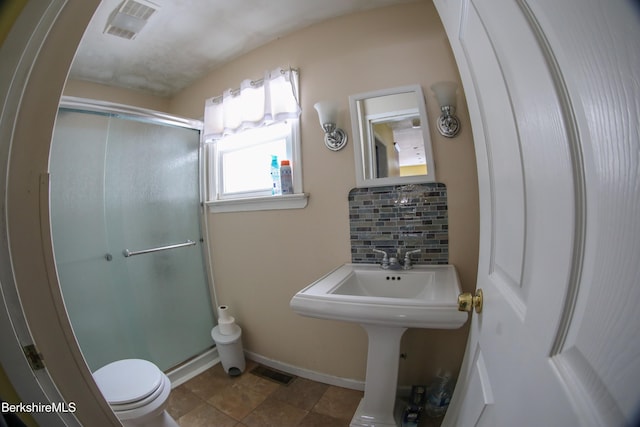 bathroom with an enclosed shower, toilet, backsplash, and tile patterned floors