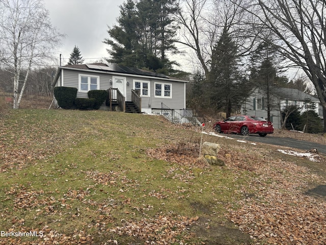 view of front of home featuring solar panels and a front lawn