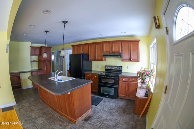 kitchen with a breakfast bar, sink, black appliances, pendant lighting, and an island with sink