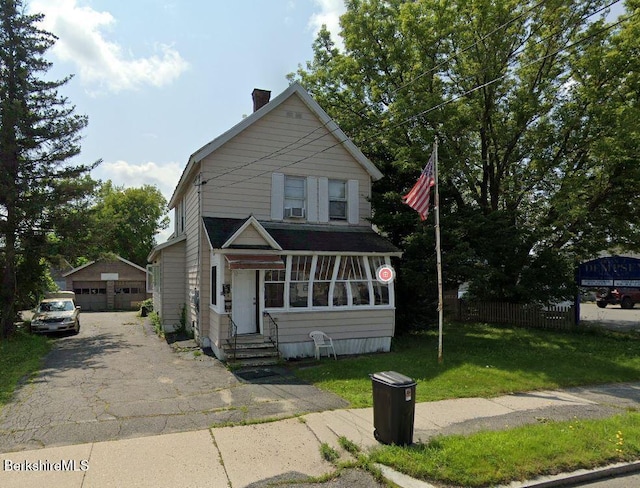 view of front of house with a garage, an outdoor structure, and a front lawn