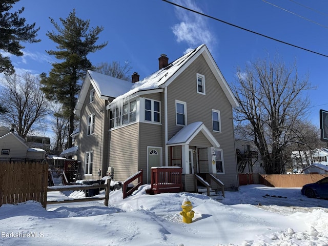 view of front facade with a chimney and fence