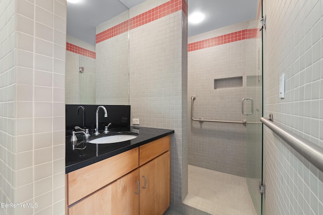 bathroom featuring tile walls, a stall shower, and vanity