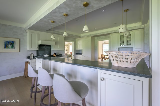 kitchen featuring pendant lighting, a kitchen breakfast bar, custom range hood, and dark wood-type flooring