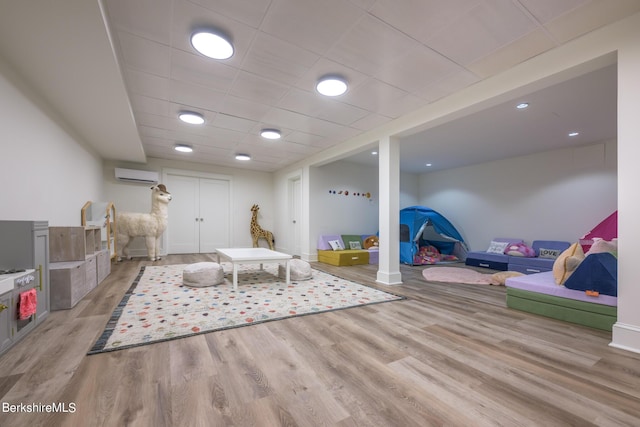 rec room with light hardwood / wood-style flooring and an AC wall unit