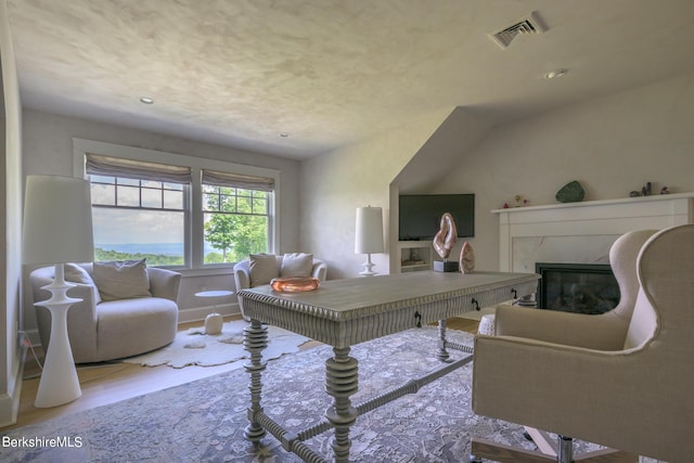 office area with lofted ceiling, a fireplace, and light hardwood / wood-style flooring