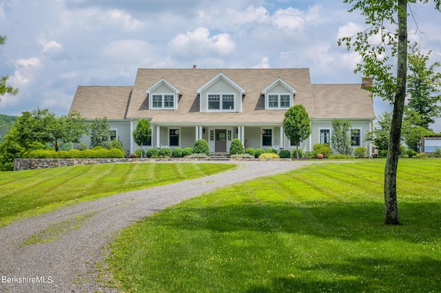 cape cod home with covered porch and a front lawn