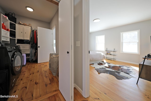 washroom with washer / dryer, baseboards, cabinet space, and light wood finished floors