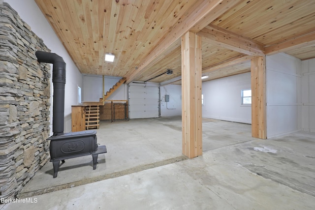 below grade area featuring a wood stove, wood ceiling, and stairway