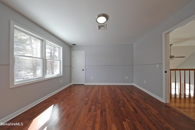 unfurnished room featuring hardwood / wood-style floors, visible vents, and baseboards