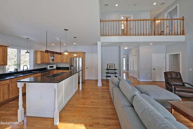 kitchen featuring white microwave, a sink, open floor plan, dark countertops, and stainless steel fridge