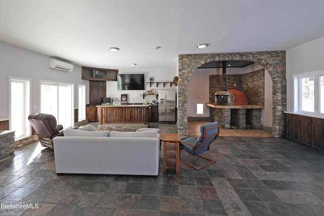 living room with stone finish flooring and a wall mounted AC