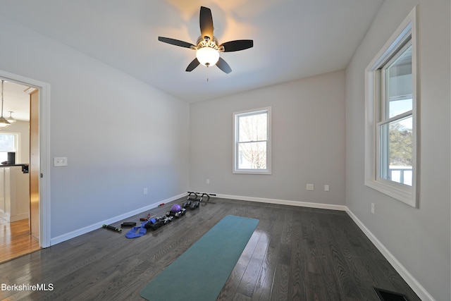 exercise room with baseboards, dark wood-style flooring, visible vents, and a healthy amount of sunlight