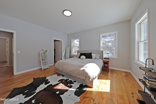 bedroom featuring multiple windows, baseboards, and hardwood / wood-style floors