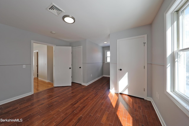 spare room featuring dark wood-type flooring, visible vents, and baseboards