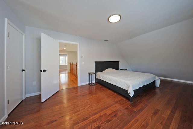 bedroom featuring lofted ceiling, visible vents, baseboards, and wood finished floors