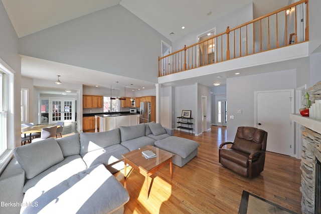 living room with light wood-type flooring, a fireplace, and high vaulted ceiling