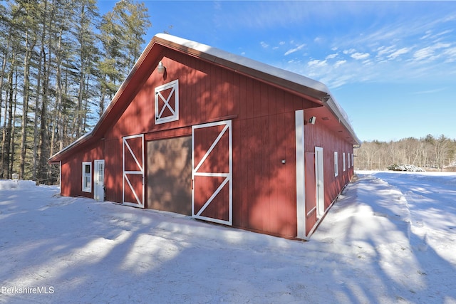 snow covered structure featuring an outdoor structure and a barn