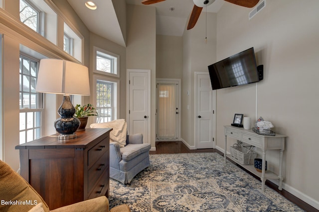 sitting room with a high ceiling, a ceiling fan, visible vents, baseboards, and dark wood finished floors