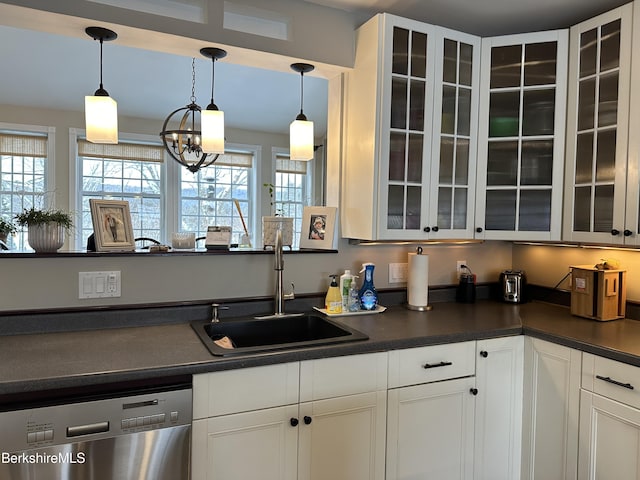 kitchen featuring dark countertops, hanging light fixtures, glass insert cabinets, a sink, and dishwasher