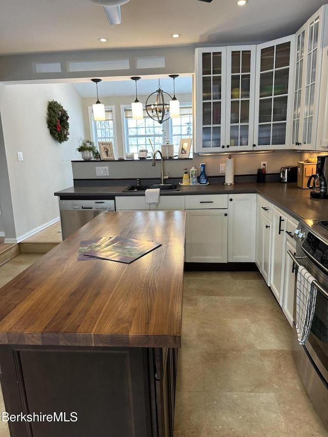 kitchen with dark countertops, glass insert cabinets, decorative light fixtures, a center island, and a sink