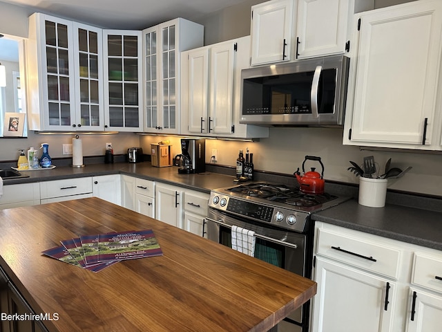 kitchen with white cabinetry, glass insert cabinets, and stainless steel appliances