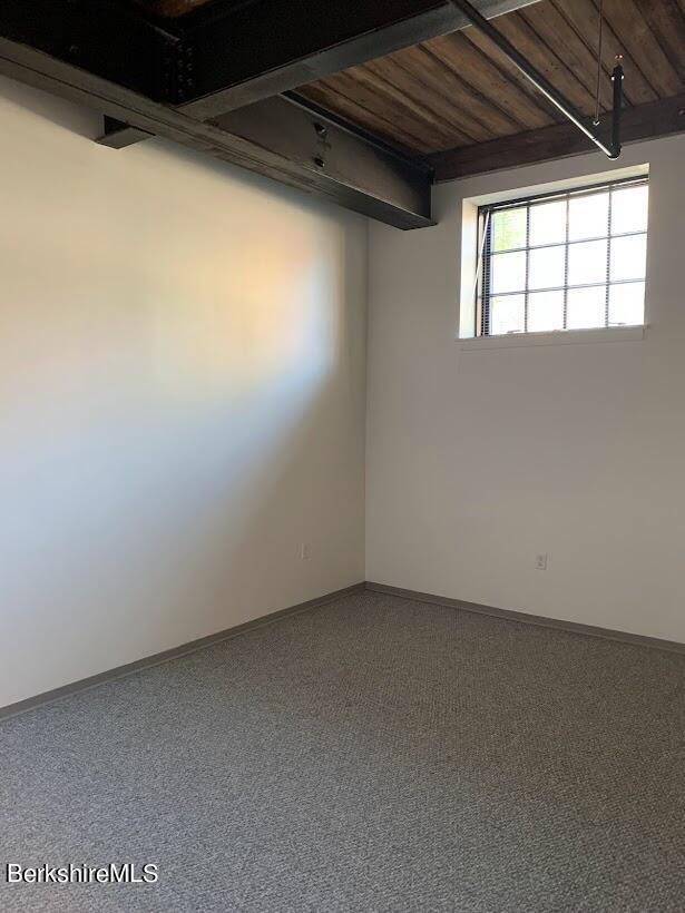 carpeted spare room with beamed ceiling and wooden ceiling
