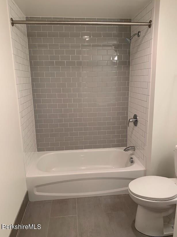 bathroom featuring tile patterned floors, tiled shower / bath combo, and toilet